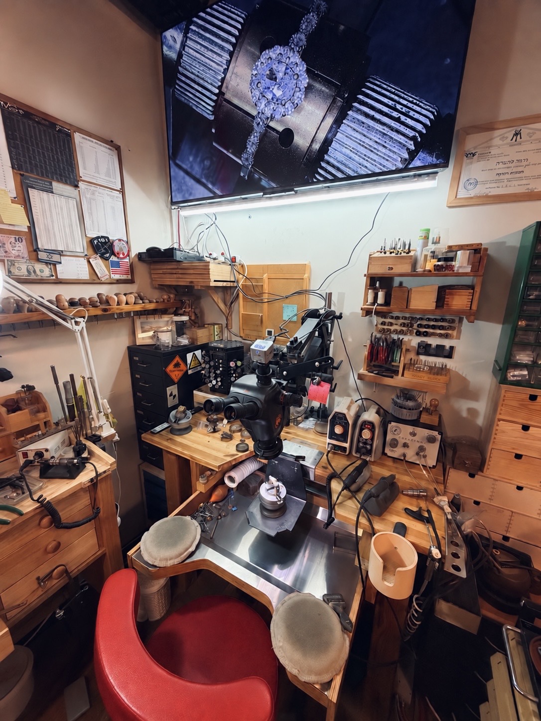 The stone setter's bench: microscope, engraving knives and tools, with the work magnified on the screen above.
