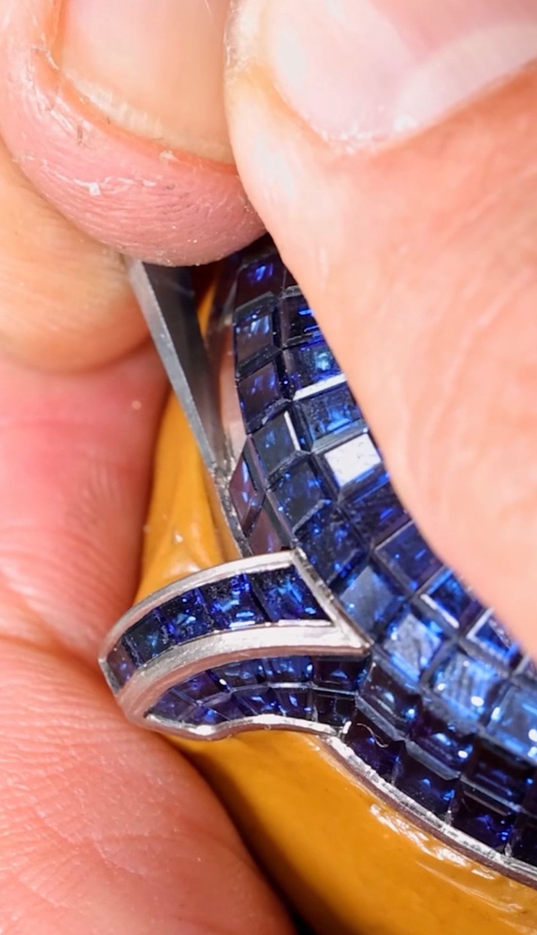 Sapphires seated on hidden rails, adjusted by hand.