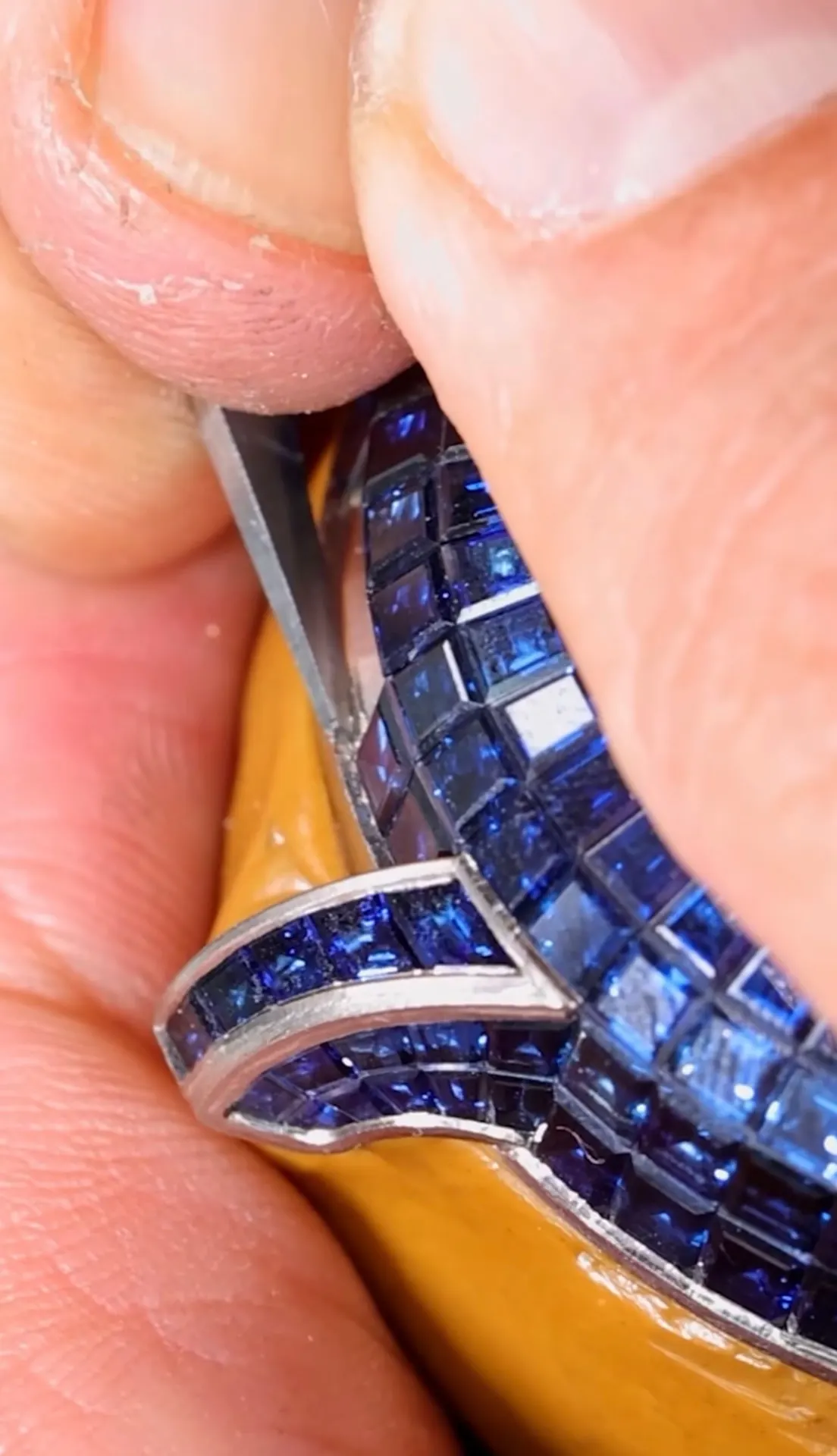 Sapphires seated on hidden rails, adjusted by hand.
