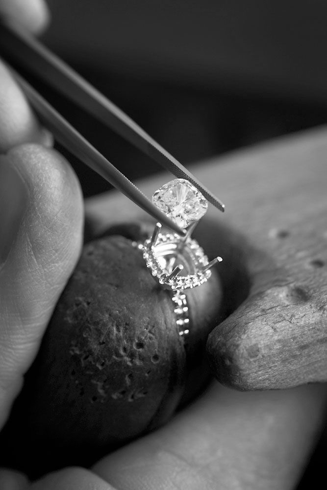 A diamond held in tweezers, a moment before it is placed into its seat.