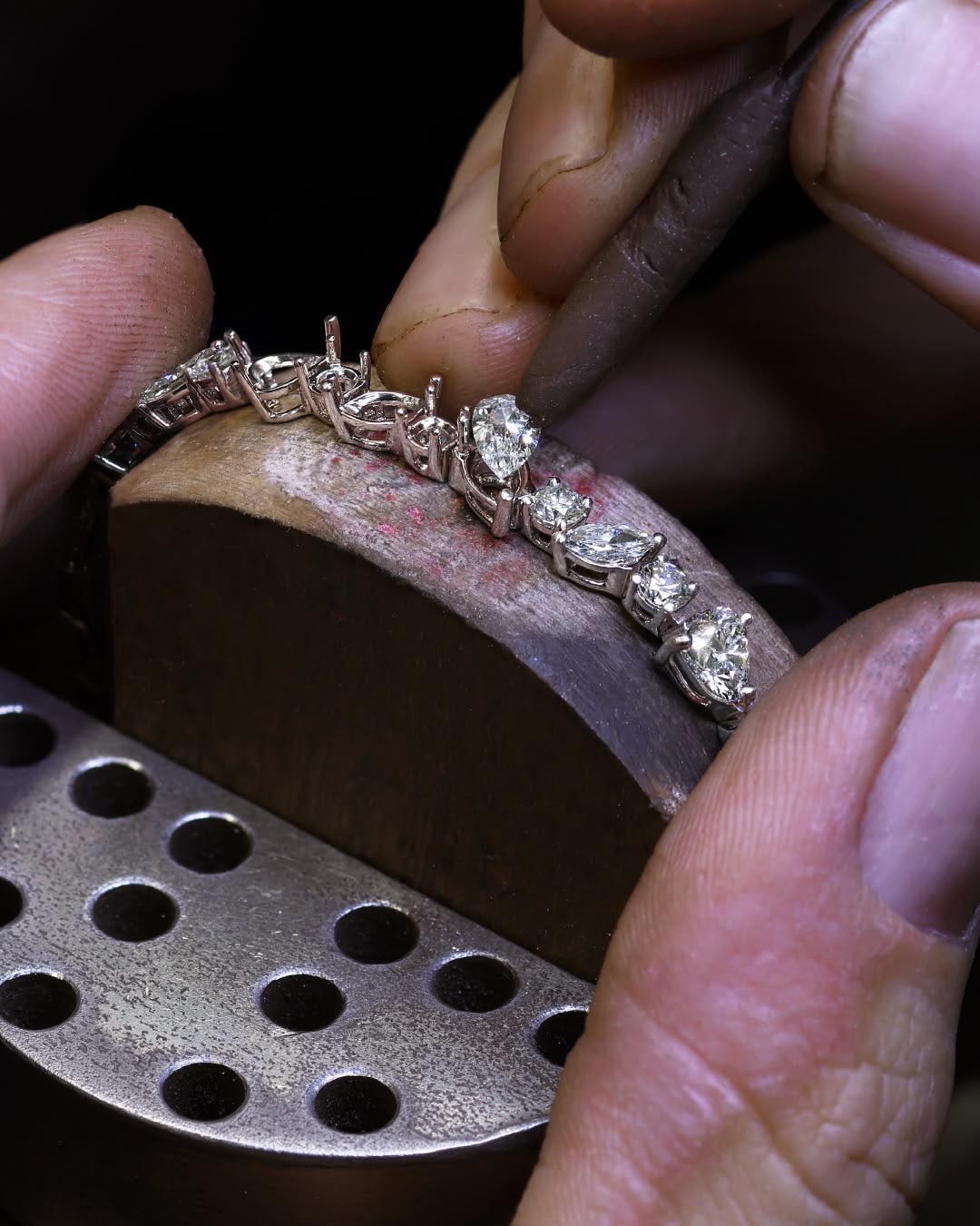 Setting stones one by one into a bracelet, each in its own seat.