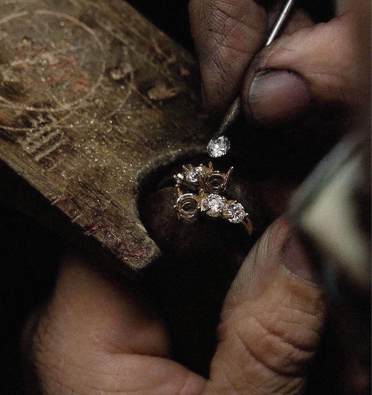 Placing a diamond into its seat, the hands steady and the metal about to close over the stone.